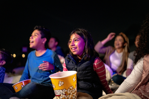 Kids laughing as they enjoy a movie and popcorn