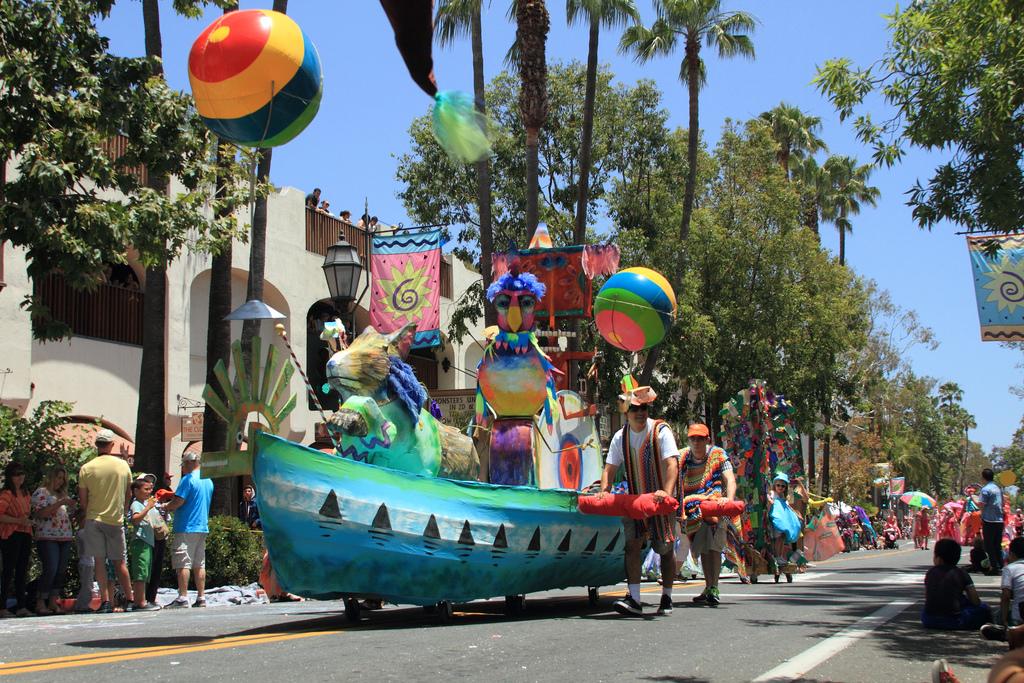 Parade float shaped like a boat with vibrant animals made out of mixed materials.