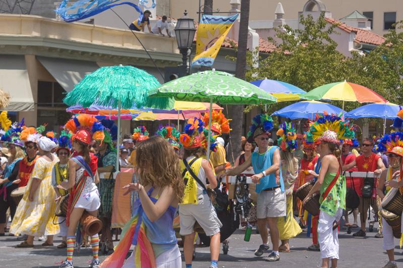 Summer Solstice Parade attendees displaying vibrant colorful umbrellas.
